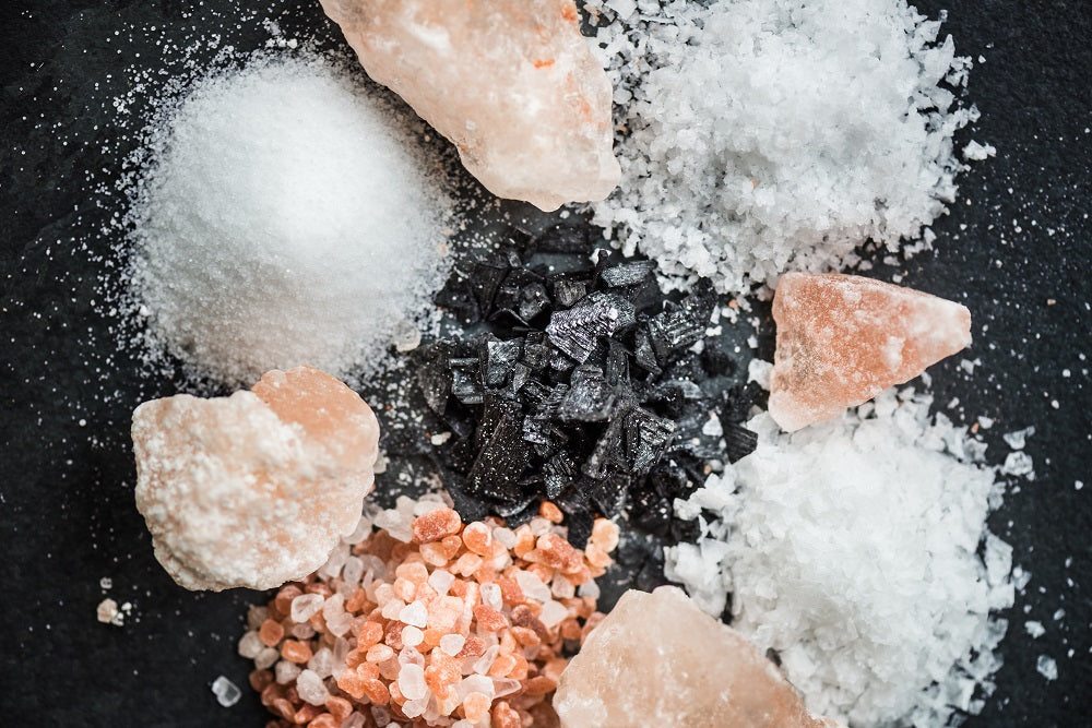 Different types of salt and salt crystals on a dark surface
