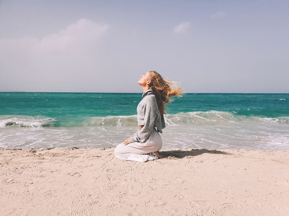 Frau sitzt am Meer