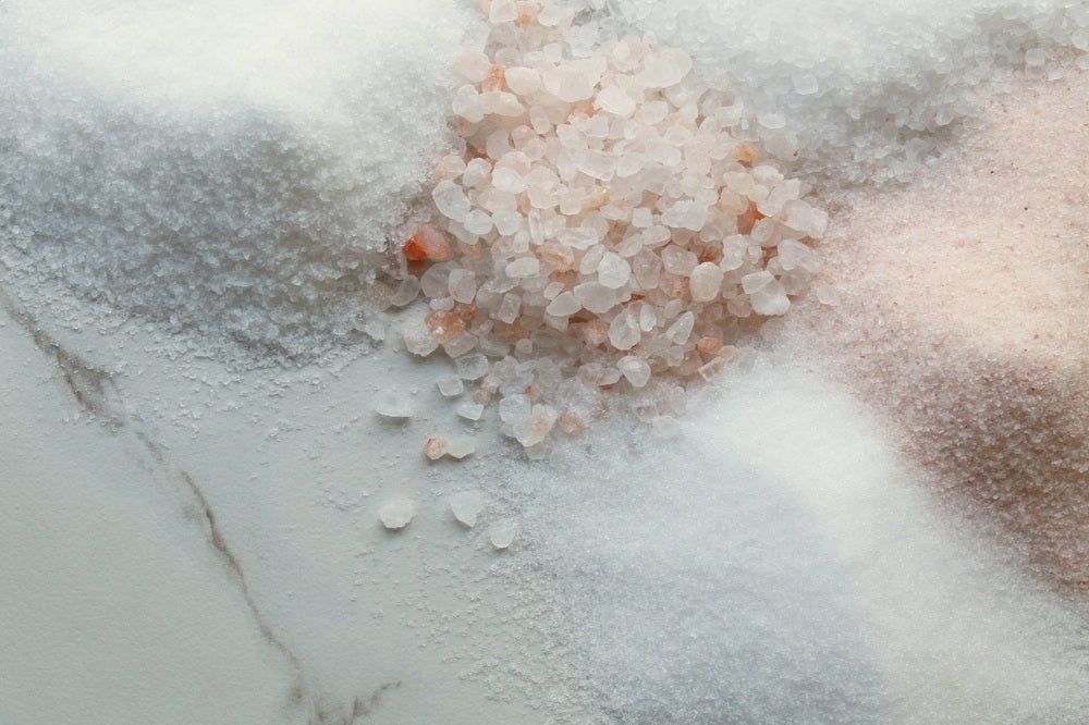 Pink salt crystals and fine white salt on marble