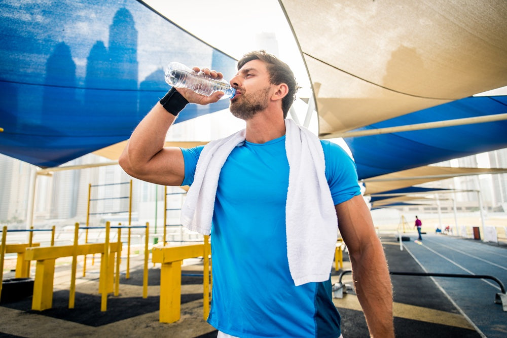 Mann trinkt Wasser beim Sport 