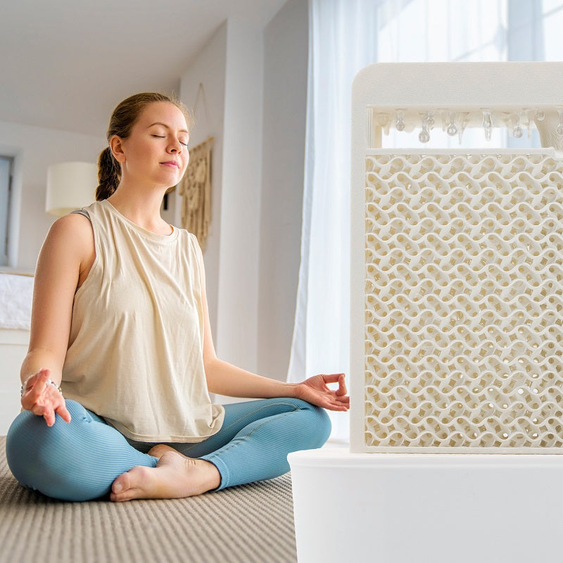 Woman sitting in the lotus position, meditating. On the right half of the picture is a white SalinoVatis in the foreground